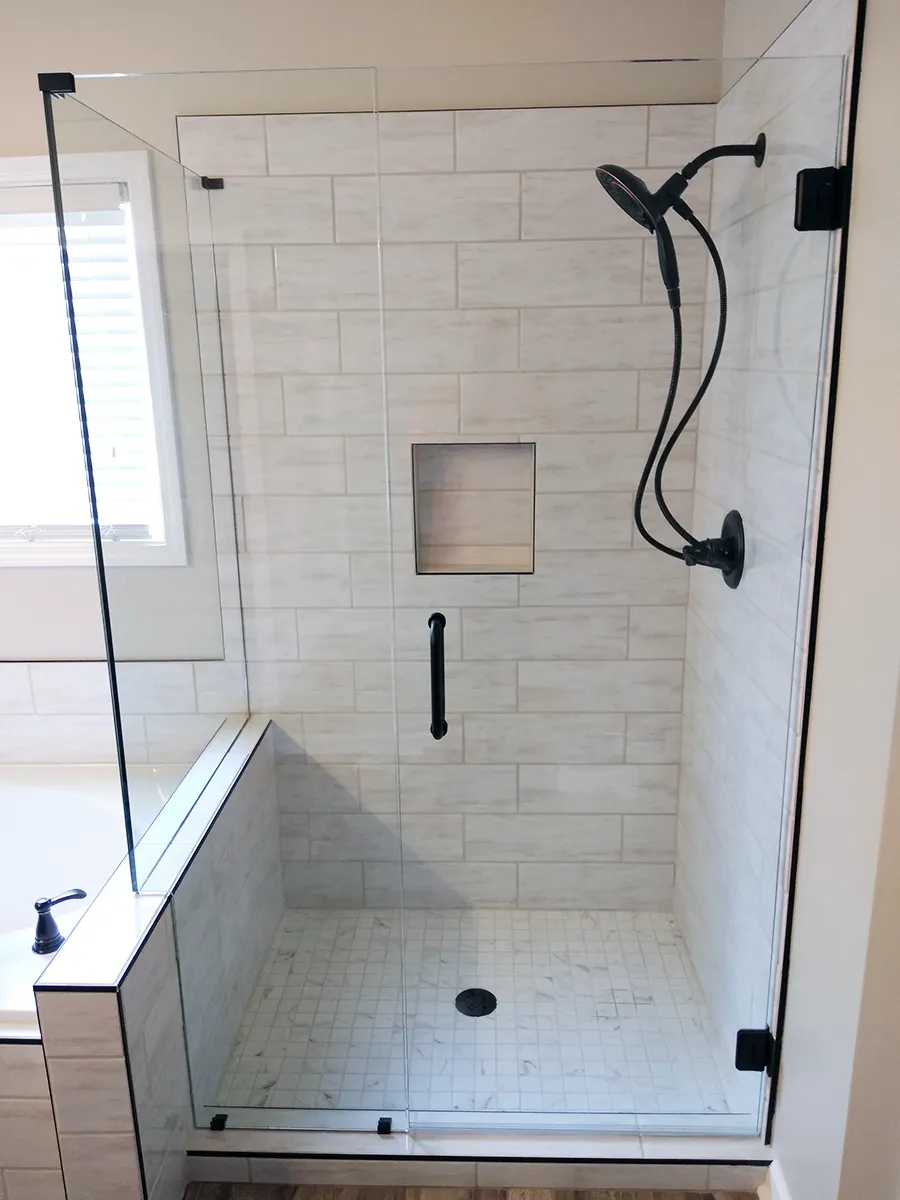 Custom 90-degree frameless shower enclosure with matte black hardware installed in a Kennesaw, GA bathroom