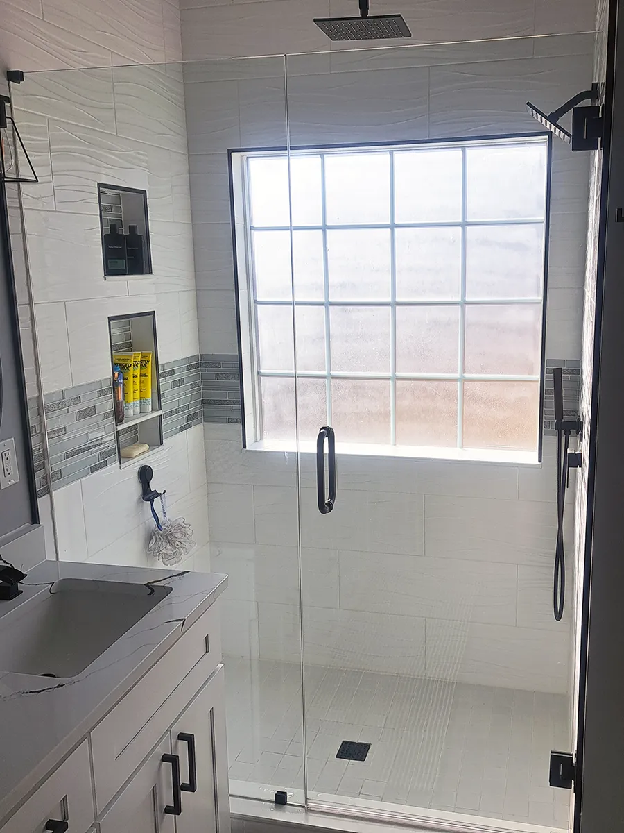 Custom inline frameless shower door and fixed glass panel with matte black hardware installed in Kennesaw, GA