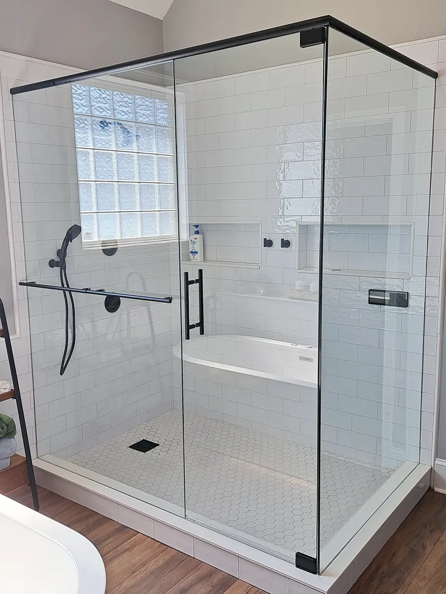 90-degree frameless shower enclosure in Woodstock, GA with matte black hardware, top header, ladder-style handle, and towel bar.